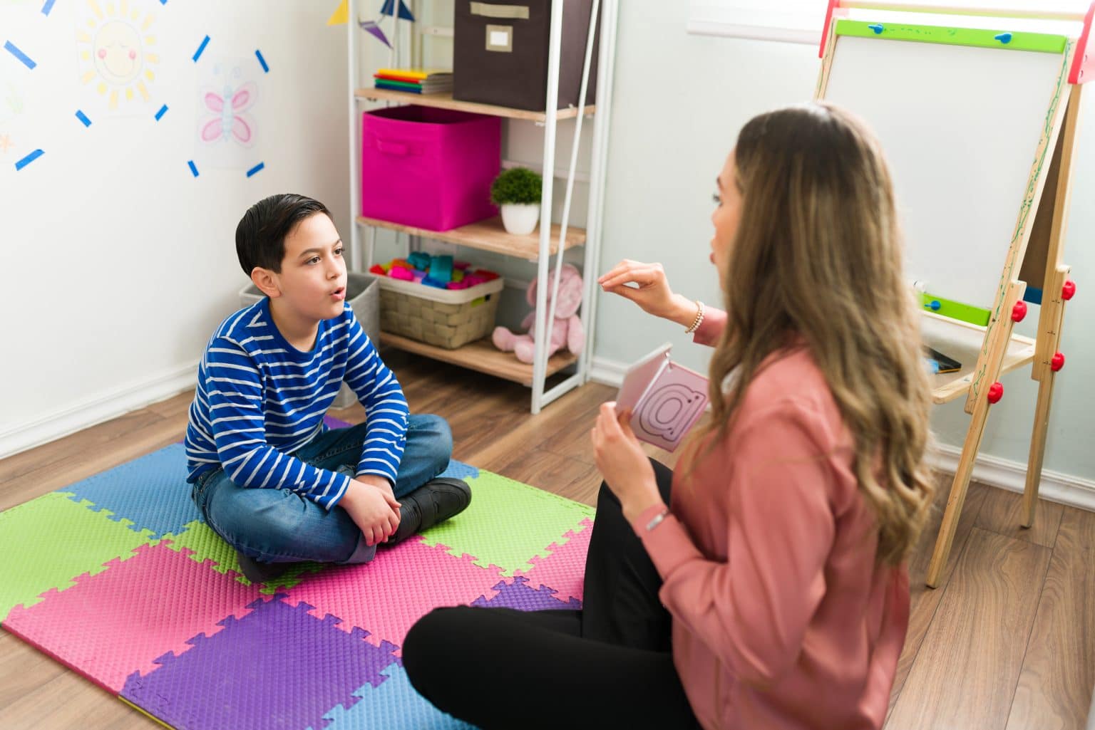 rozpoznawanie emocji na kartach w sesji terapeuta pokazujący kartę z uśmiechniętą twarzą dziecku głuchemu
