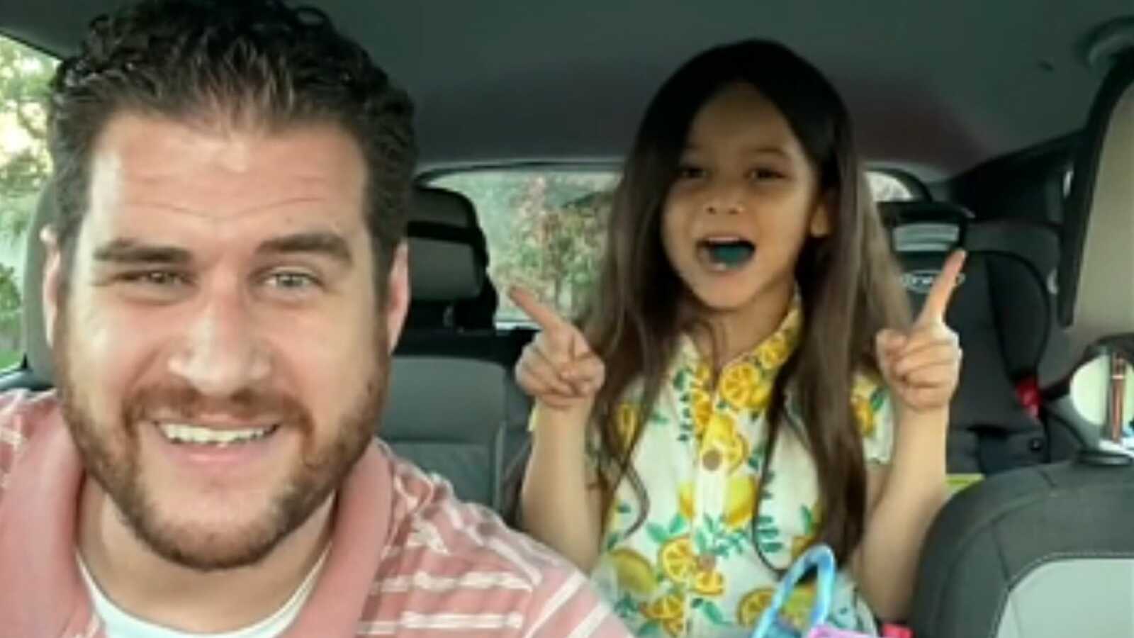 Dziecko z aparatem słuchowym wskazuje na kolorową mapę podróży z rodzicami