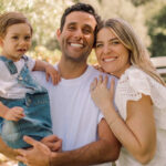 Jak spakować aparaty słuchowe na podróż samolotem z dzieckiem niedosłyszącym? Uśmiechnięta rodzina z dzieckiem w aparacie słuchowym na plaży podczas wakacji